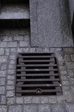Storm Drain Embedded in Cobblestone Pavement of an Old Town Stock Photos