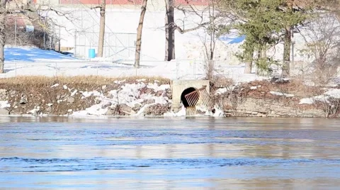 Storm drain flows into winter river Video stock 59698472