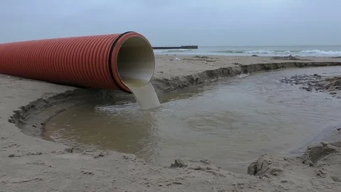 Storm drain water flowing from the plastic pipe to the sea Stock Footage 70365345
