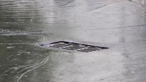 Storm drain on wet asphalt surface during heavy rain shower water flowing into Video stock 344094150