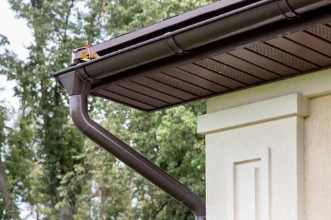 Storm drainage gutter at the corner of  building brown plastic shower pipe. Stock Photos