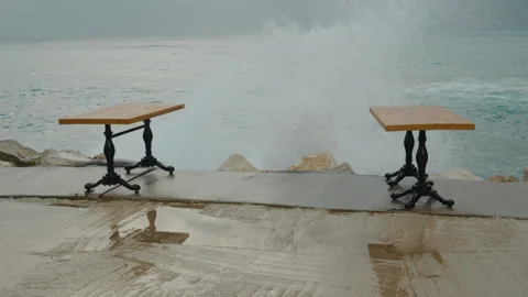Storm at sea, and a large wave is approaching the tables of a restaurant on the Stock Footage 262247730