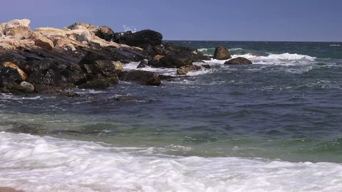 Storm on the sea, transparent waves roll on the sand and break on the rocks Stock Footage 90898659