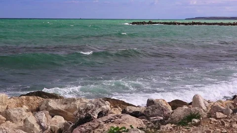 Storm on the sea, transparent waves roll on the sand and break on the rocks Video stock 103477658