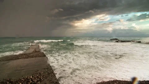 Storm surges rolled up on a pebbly beach, in the frame breakwaters. Long shot Stock Footage 217725420