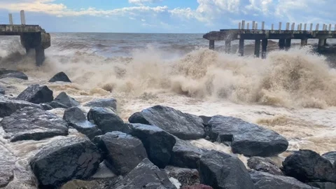 Storm waves crashing in wide view against rocks and pier structures Stock Footage 345361672
