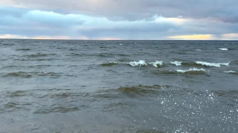 Storm waves splash against the shore under an overcast sky. Dramatic clouds.. Stock Footage 320909901