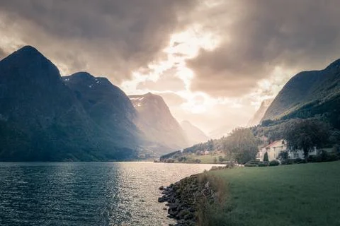 Stormclouds with sun shining through them above dramatic mountain range of Stock Photos