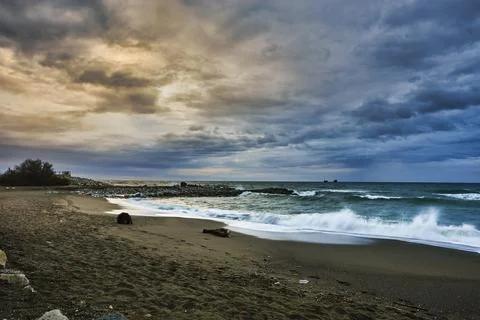 Stormy beach scene displaying rough ocean waves and dramatic clouds Fotos de archivo