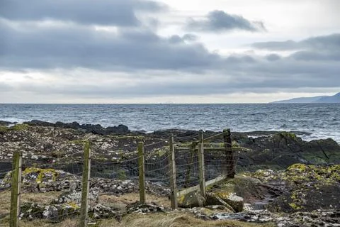 Stormy clouds loom over a rugged, rocky shoreline Foto stock