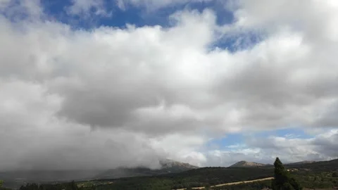 Stormy clouds moving fast over a small town nestled in a green mountain valley Stock Footage 343781735