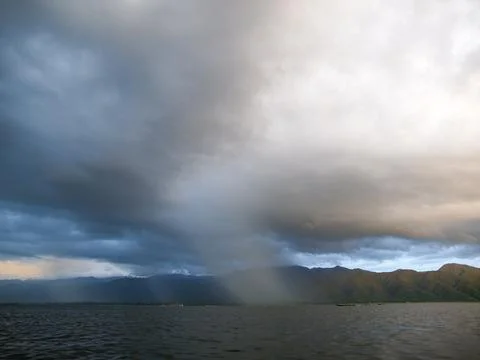 Stormy, cloudy sunset over Inle Lake in Myanmar, dramatic sky with dark rain Stock Photos