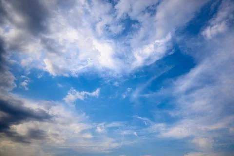 Stormy grey cloud with puffy white ones and blue sky. Stock Photos