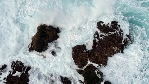Stormy ocean waves hitting black rocks and producing a lot of white foam and Stock Footage 129008554