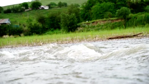 A stormy river flows fast against the background of the village Stock Footage 136303707
