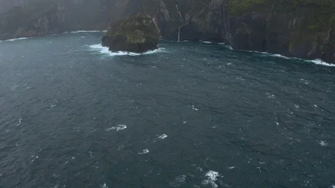 Stormy sea and cliffs of cloudy San Miguel island. Waterfall falls into ocean Stockbeeldmateriaal 119892233