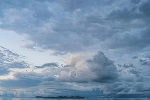 A stormy sea under dramatic, layered clouds, reflected calm waters, hint of d Stock Photos