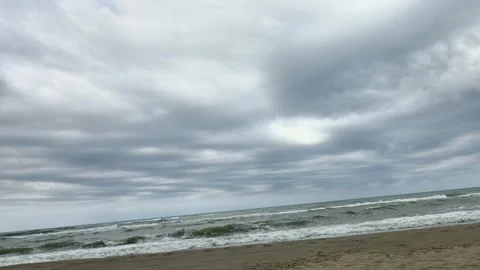 Stormy Sea Waves Rolling Onto Sandy Beach Under a Dramatic Cloudy Sky Vídeos de archivo 343490414
