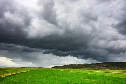 Stormy sky casts shadow over rolling green fields with no visible life forms Stock Photos