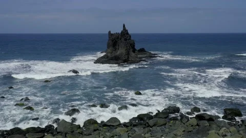 Stormy waves roll over the rocky shore. black rocks of frozen magma stick out of Stock Footage 231496752