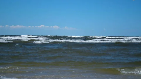 Stormy waves slowly rolling onto beach on a sunny day minimalistic background 库存影片 92993173