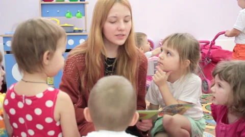 Storytime - a elementary school teacher reading a story to a group of children 스톡 동영상 62197337
