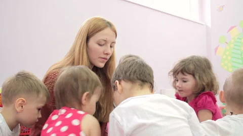 Storytime - a elementary school teacher reading a story to a group of children 스톡 동영상 62197452