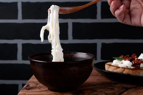 Stracciatella cheese on the fork is picked up from the bowl Foto stock