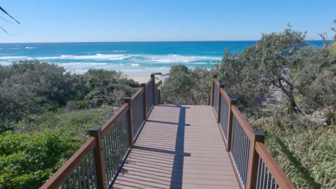 Stradbroke Island POV Walking Down Boardwalk Steps Toward Ocean Beach 4K Stock Footage 336554847