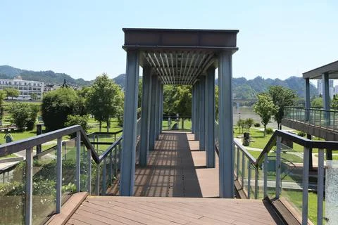 Straight covered walkway frames a distant green hillside in a quiet outdoor.. Stock Photos