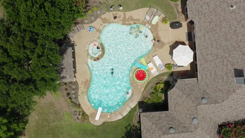 Straight down aerial drone view of backyard swimming pool with people swimming 스톡 동영상 248078444
