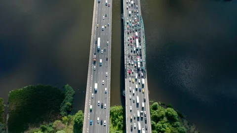 Straight motion through the bridge with big traffic over the river under clouds. Video stock 140272556