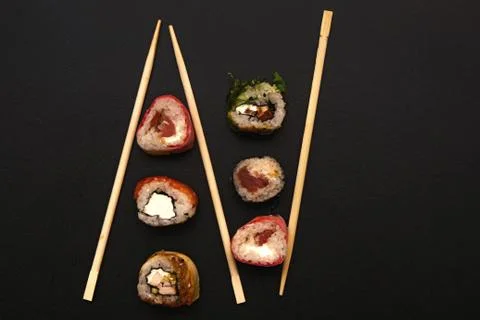 Straight parallel vertical lines of sushi and chopstick on black background. Stockfoto's