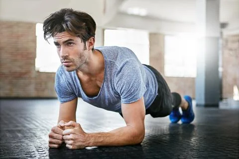 Straight as a plank. a young man working out in the gym. Stock Photos