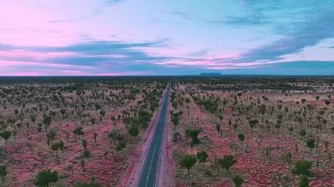 A straight road cutting through the red outback desert heading towards the Stock Footage 202487901