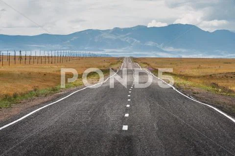 Straight road goes to horizon and mountains Stock Photos