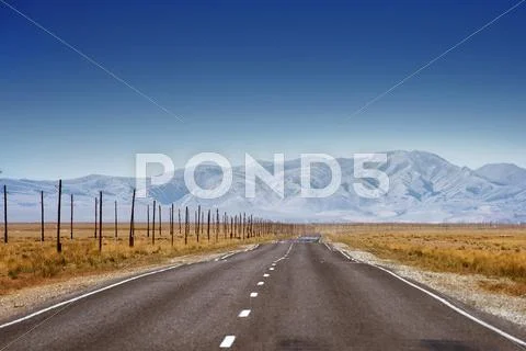 Straight road goes to horizon on mountains backdrop Stock Photos