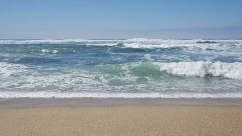 Straight on waves breaking on sandy beach in Portugal on a sunny day Stock Footage 104458982
