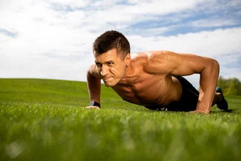 Strained man is doing press-ups on lawn Stock Photos