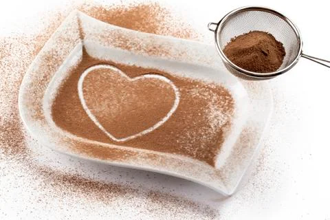 Strainer with cocoa while heart shape on a white container Stock Photos