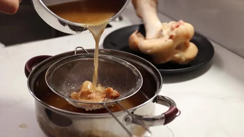 Straining Bone Broth for Clarity: Pouring Through a Fine-Mesh Sieve to Stock Footage 344031730