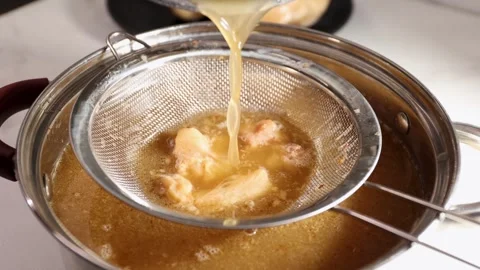 Straining Bone Broth: Clear Liquid Separation Through a Fine-Mesh Sieve into a Stock Footage 344031865