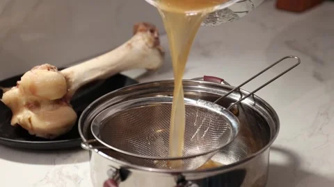 Straining Bone Broth: Separating Clear Stock Through a Fine-Mesh Strainer Stock Footage 344031812
