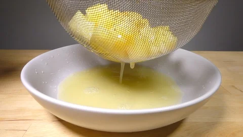 Straining pineapple chunks, with the juice flowing into a bowl. Stock-Footage 114121724