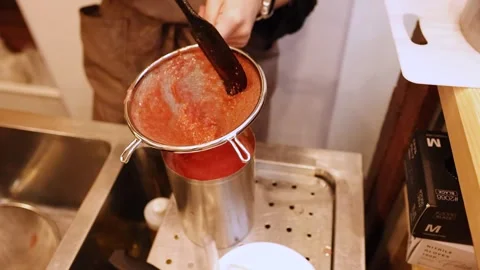 Straining pureed tomatoes through a sieve into a metal container for making.. Stock Footage 333223595