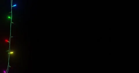Strand of coloured christmas string lights flashing on black background, copy Stock Footage 253158393