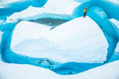 Stranded on a large ice fin, a man stands on top looking at the lake surround Stock Photos