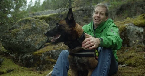 Stranded man stroking a rescue dog in forest Stock Footage 86248553