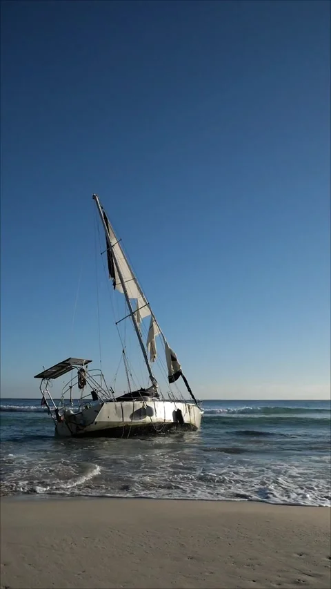 Stranded sailboat on the beach shore Stock Footage 259888642
