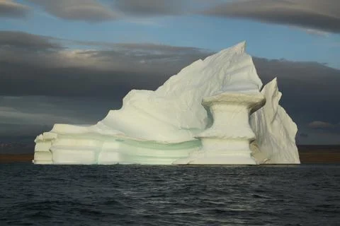 Stranded tabular iceberg and ice near evening in arctic landscape, near Pond Stock Photos